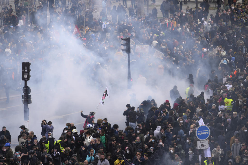 Protesters are seen through tear gas a demonstration, Thursday, April 13, 2023 in Paris. Protesters opposed to President Emmanuel Macron's unpopular plan to raise the retirement age in France marched Thursday in cities and towns around France in a final show of anger before a decision by the Constitutional Council on whether the measure meets constitutional standards. (AP Photo/Thibault Camus)