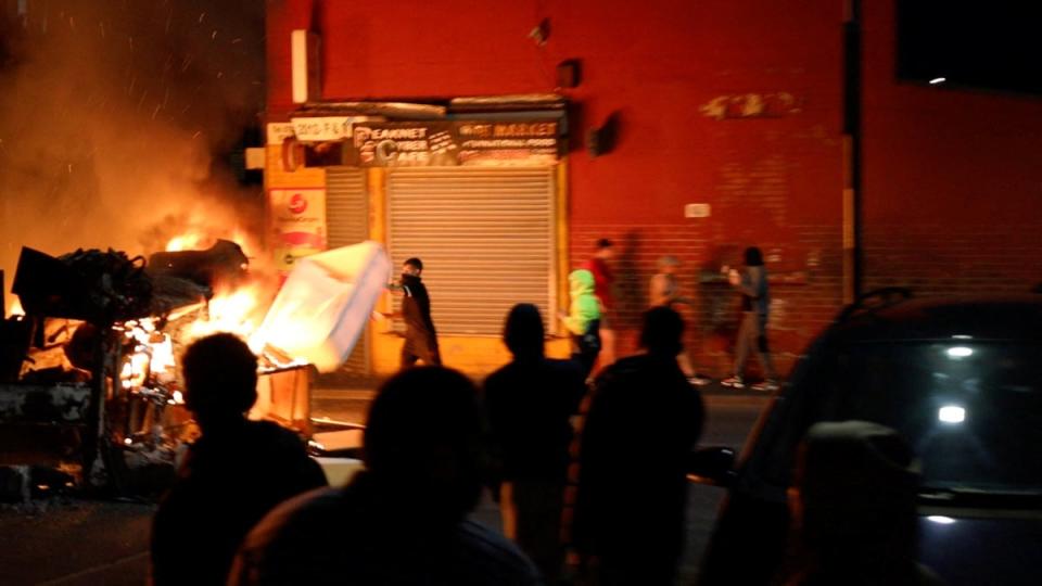 A man throws an item onto a fire during unrest in Harehills, Leeds (@robin_singh/Instagram via Reuters)