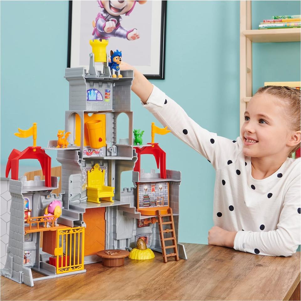 child playing with gray plastic toy castle