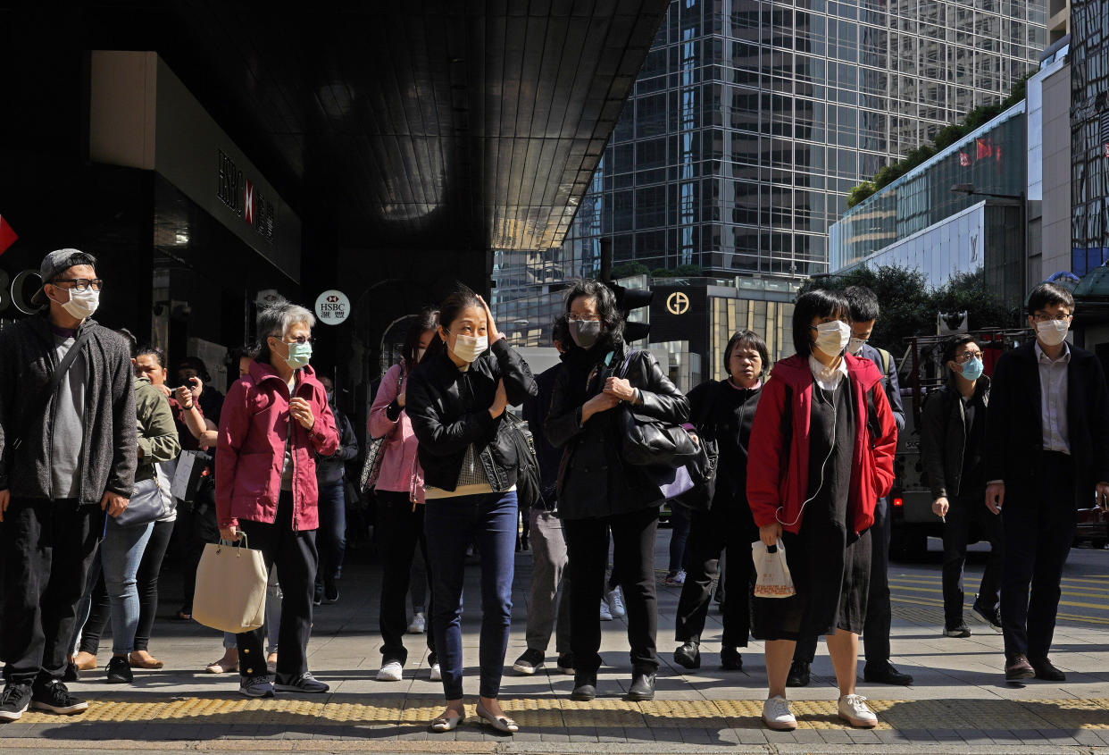 People wearing face mask walk at a downtown street in Hong Kong Friday, Feb. 21, 2020. COVID-19 viral illness has sickened tens of thousands of people in China since December. (AP Photo/Vincent Yu)