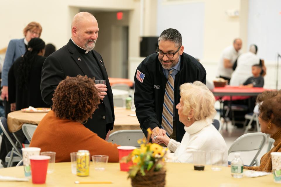 Rev. Joseph D'Amico, left, talks with Mayor Michael Pagan, right, and other guests during a Thanksgiving potluck, organized by Teaneck Interfaith Community, at St. Anastasia Church in Teaneck on Sunday, November 19, 2023.