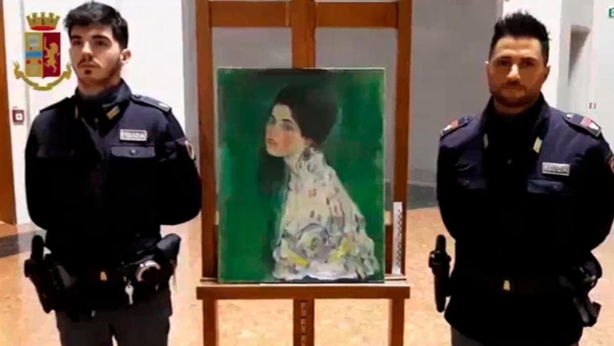 Two police officers stand guard next to a painting – believed to be a stolen artwork by Gustav Klimt – discovered in a cavity in a gallery's walls, in Piacenza, northern Italy: AP