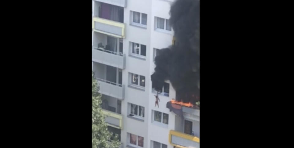In this grab taken from video, a boy hangs from a window as flames engulfed an apartment as onlookers below prepare to catch him, in Grenoble, France, Tuesday, July 21, 2020. A boy and a toddler escaped a blaze at an apartment in the southeastern French city of Grenoble on Tuesday after they jumped into the arms of residents. The two brothers, aged three and 10 years old, were hanging from a window as flames engulfed their home and onlookers below screamed for them to jump down. (AP)