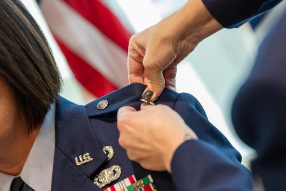 Airman 1st Class Laura Kate Ahaesy and Airman 1st Class Julia Ahaesy, pin the rank of brigadier general on their mother newly promoted Brig. Gen. Lisa Ahaesy during her promotion ceremony at the Massachusetts National Guard Joint Forces Headquarters, Hanscom Air Force Base, on Dec.12, 2023.
