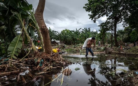 A man walks through debris after hit by tsunami as they carry their belongings