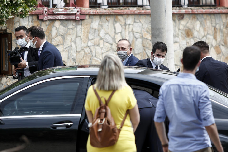 Turkish Foreign Minister Mevlut Cavusoglu, back center, arrives at a restaurant at village Thamna, near Komotini, in northeastern Greece, Sunday, May 30, 2021. Greece's prime minister said Friday his country is seeking improved ties with neighbor and longtime foe Turkey, but that the onus is on Turkey to refrain from what he called "provocations, illegal actions and aggressive rhetoric." (AP Photo/Giannis Papanikos)