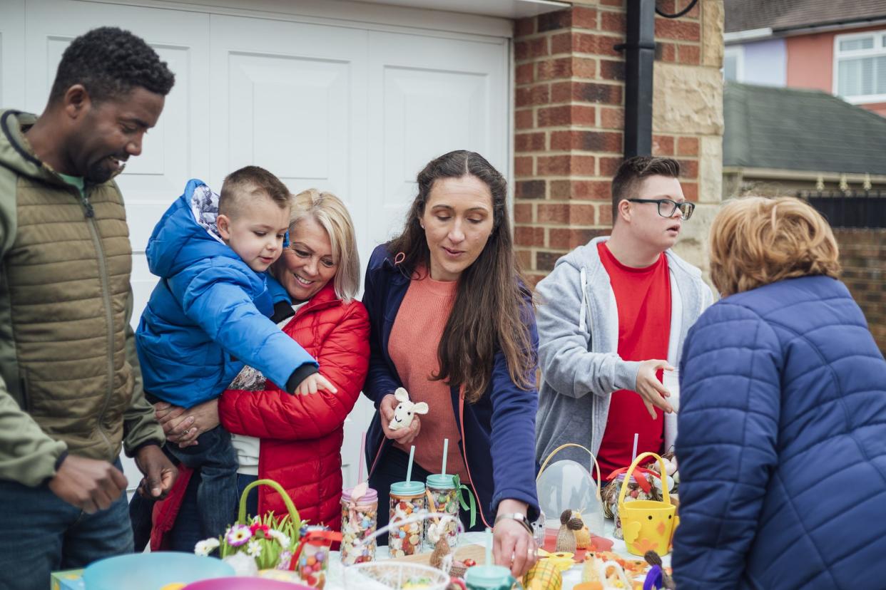 Family having an Easter yard sale in their garden in the North East of England. They have hand made easter crafts on a table and chocolate snacks. One of the sellers has down syndrome.