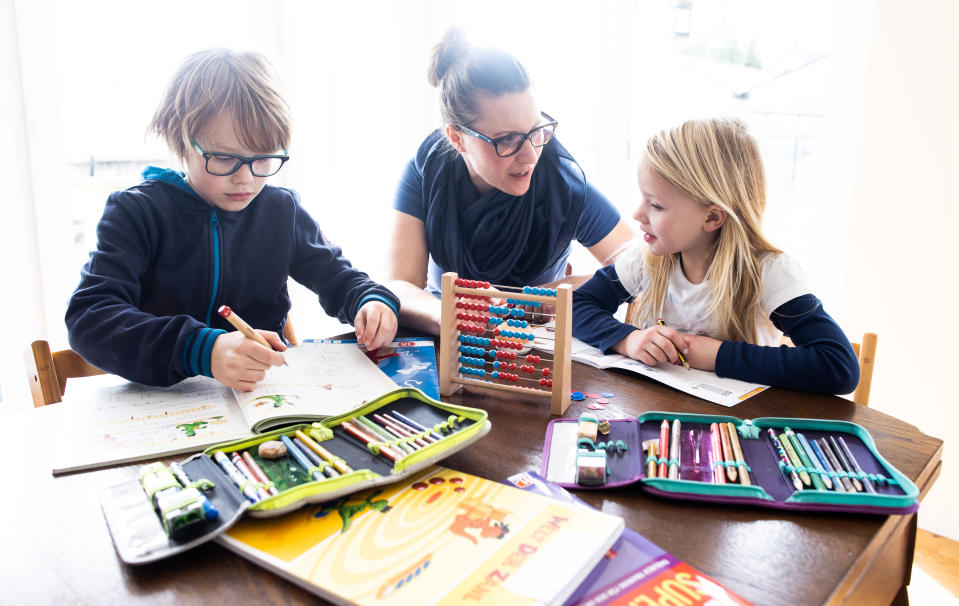 A mother helps her nine-year-old son and six-year-old daughter to do school homework on March 15, 2020 in Dinslaken, Germany. As the number of confirmed cases of coronavirus infection continues to rise daily across Germany so is the impact of the virus on everyday life. Businesses are increasing home office work, airlines are decreasing their flight capacity, schools with cases of the virus are closing temporarily, some sports events are void of spectators, shops are selling out of disinfectants and large-scale public events are being cancelled. (Photo by Lars Baron/Getty Images)