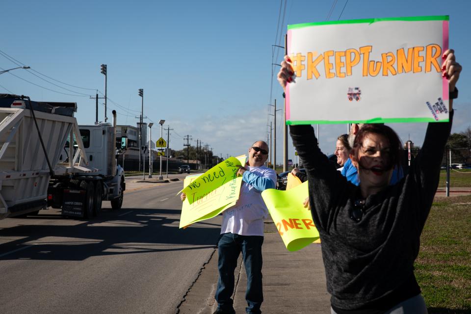 Parents Jessica Harman, front right, Richard Gordon, back left, hold signs and ask traffic for honks outside of Gregory-Portland High School on Wednesday, Feb. 21, 2024, in Portland, Texas.