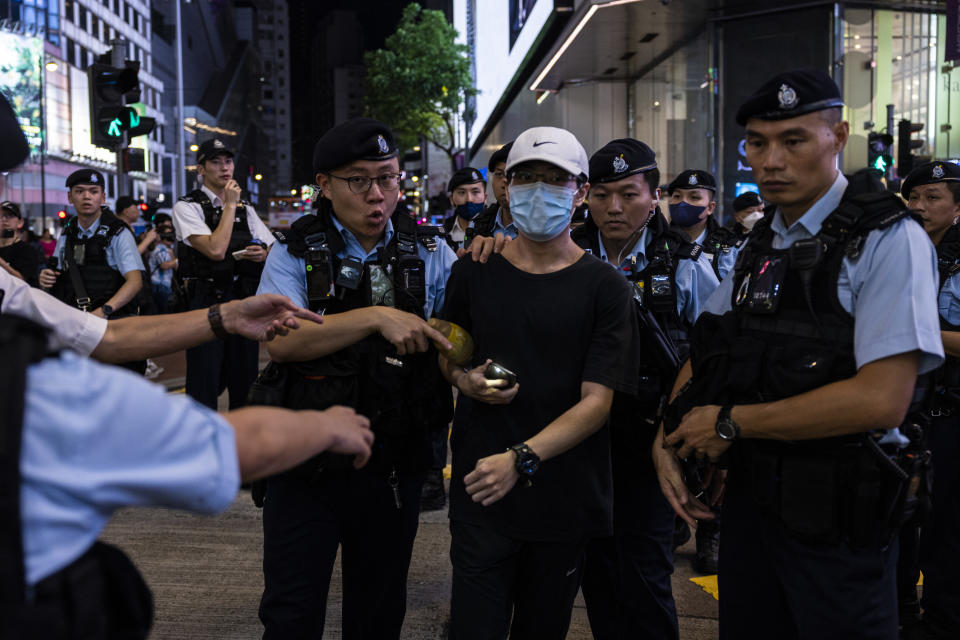 A member of the public is escorted by police after shining the light from a smartphone, near Victoria Park, the city's venue for the annual 1989 Tiananmen massacre vigil, on the 34th anniversary of China's Tiananmen Square crackdown in Hong Kong, Sunday, June 4 2023. (AP Photo/Louise Delmotte)