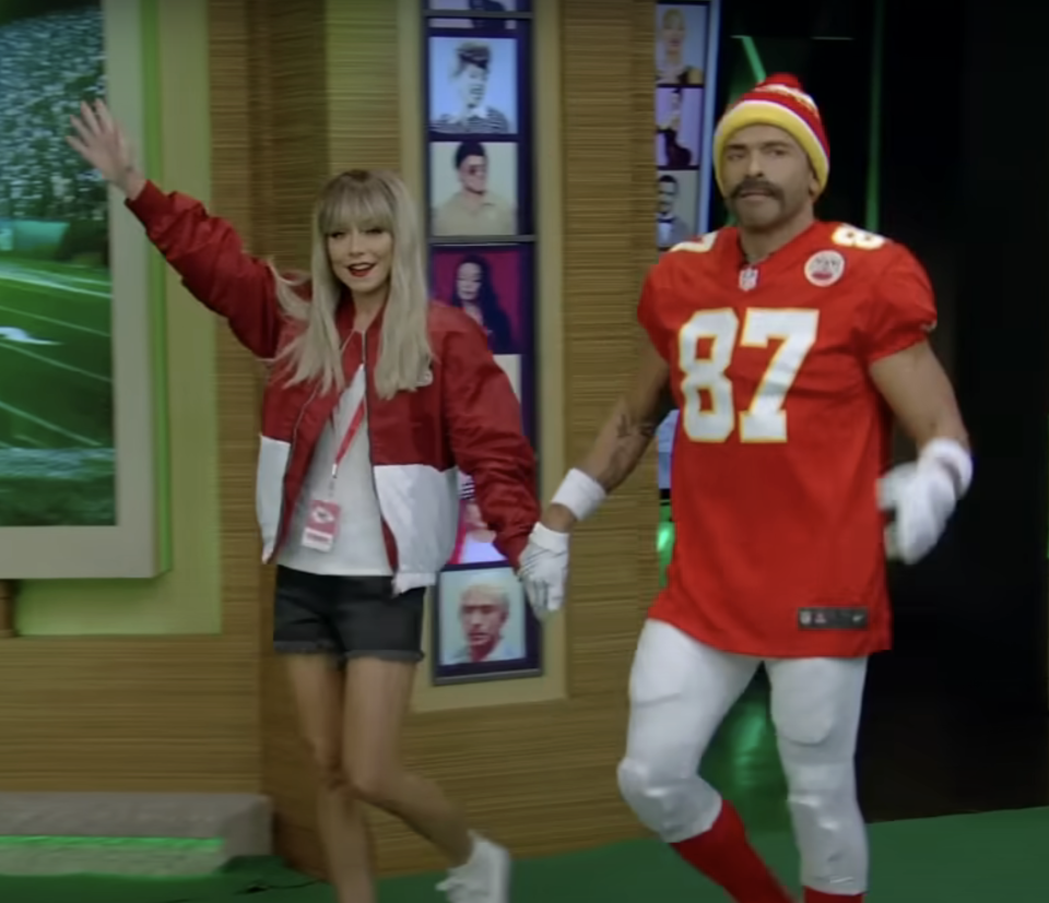 she's wearing a badge and team colors and he's wearing the football uniform