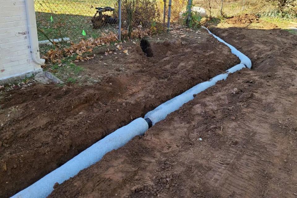 A close up of a section of a french drain laid in dirt. 