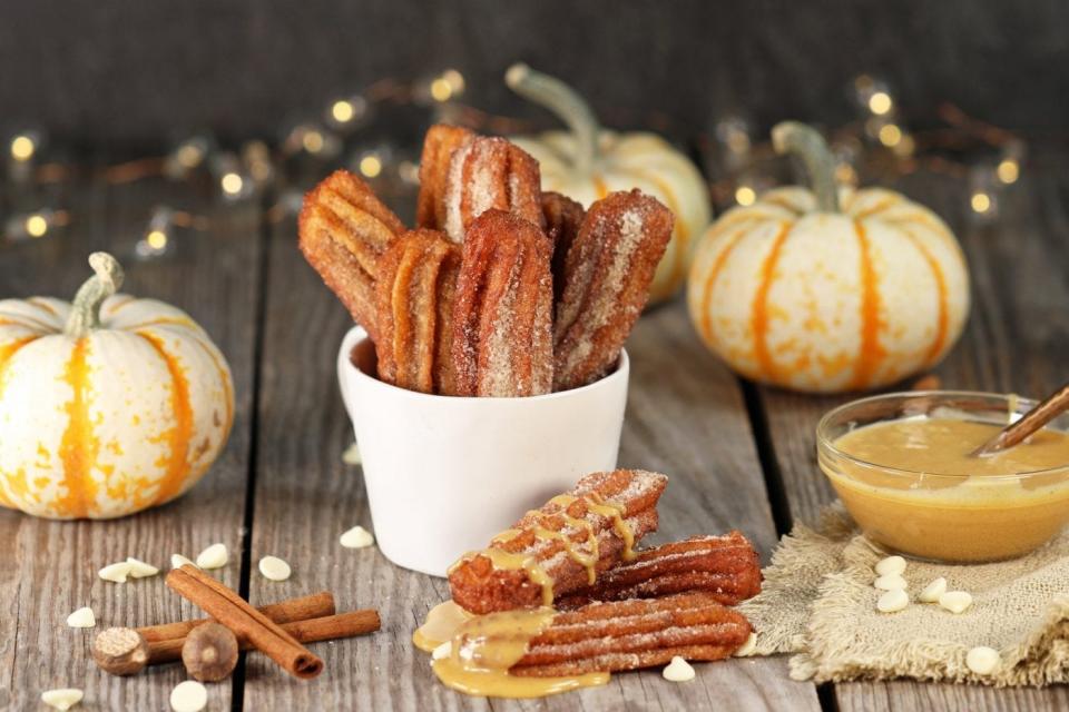 Pumpkin spice churros drizzled with pumpkin sauce in a bowl.