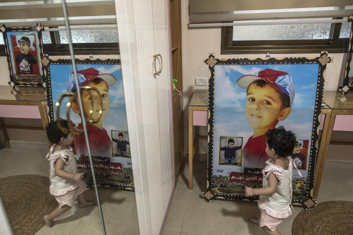 Noor Nijim, looks at a picture of her slain brother Jameel, in her bedroom in the family home in Jebaliya, Tuesday, Aug. 16, 2022. A Palestinian human rights group and an Israeli newspaper reported Tuesday that an explosion in a cemetery that killed five Palestinian children during the latest flare-up in Gaza was caused by an Israeli airstrike and not an errant Palestinian rocket. (AP Photo/Fatima Shbair)