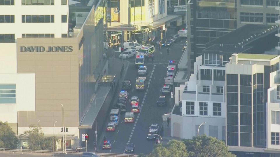 In this image made from video provided by AUBC, first responders gather near the scene of a stabbing at a shopping center in Sydney, Australia, Saturday, April 13, 2024. Media reports say multiple people have been stabbed and that the police shot at least one person at a Sydney shopping center. (AUBC via AP)