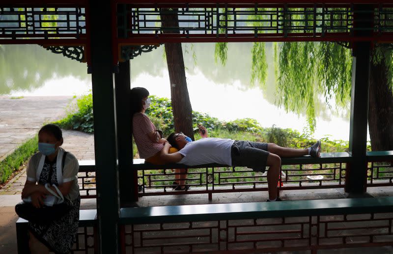 People wearing protective masks relax in the park at Summer Palace on a public holiday, after a new outbreak of the coronavirus disease (COVID-19), in Beijing