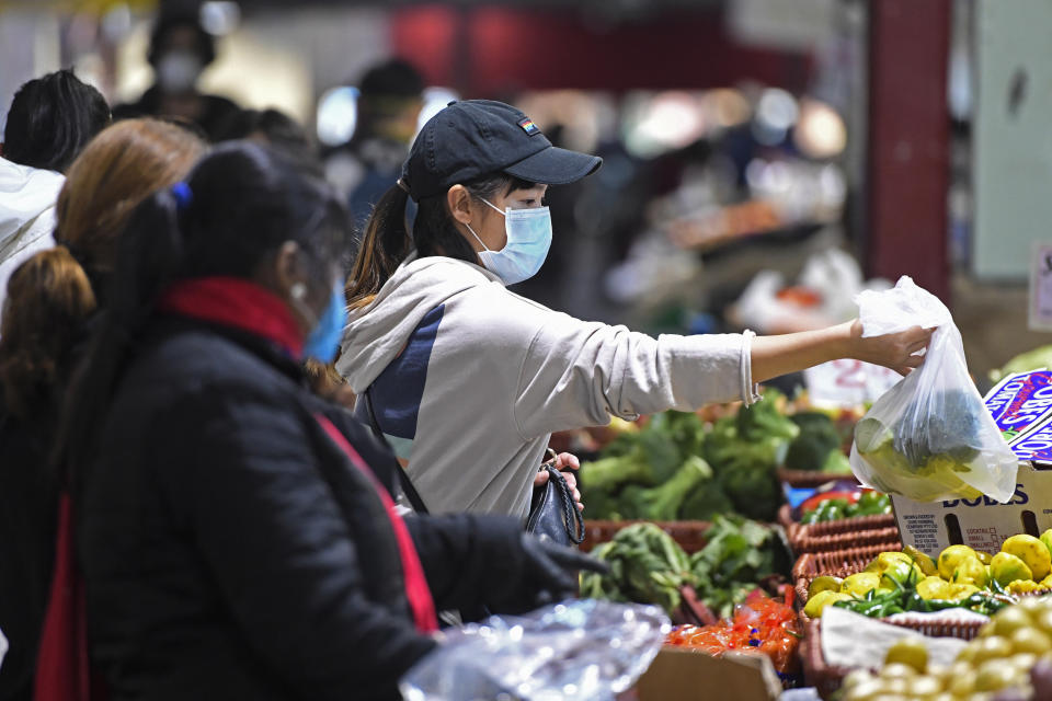 People shop at Queen Victoria Market hours before a citywide curfew is introduced in Melbourne, Sunday, Aug. 2, 2020. The premier of Australia’s hard-hit Victoria state has declared a disaster among sweeping new coronavirus restrictions across Melbourne and elsewhere from Sunday night. (Erik Anderson/AAP Image via AP)