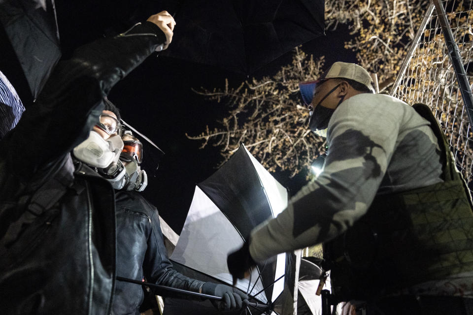 A Black man argues with demonstrators to stop preparing to use umbrellas to press against a perimeter security fence to agitate authorities during a protest decrying the shooting death of Daunte Wright outside the Brooklyn Center Police Department, Friday, April 16, 2021, in Brooklyn Center, Minn. (AP Photo/John Minchillo)