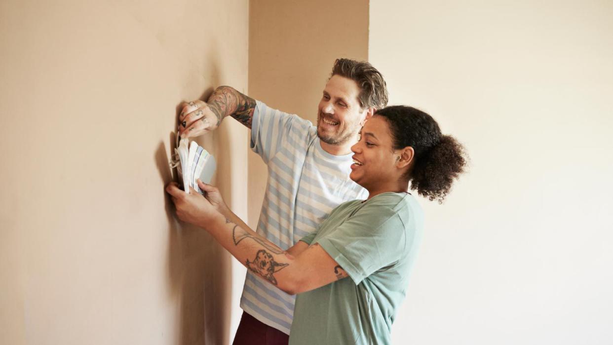 A smiling couple choosing paint color for home