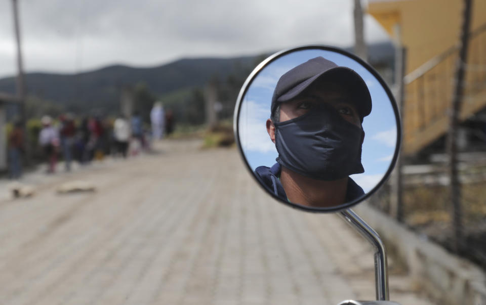 A man wearing a mask to help curb the spread od the new coronavirus is reflected in the mirror of his motorcycle in Cariacu, Ecuador, Wednesday, June 17, 2020. (AP Photo/Dolores Ochoa)