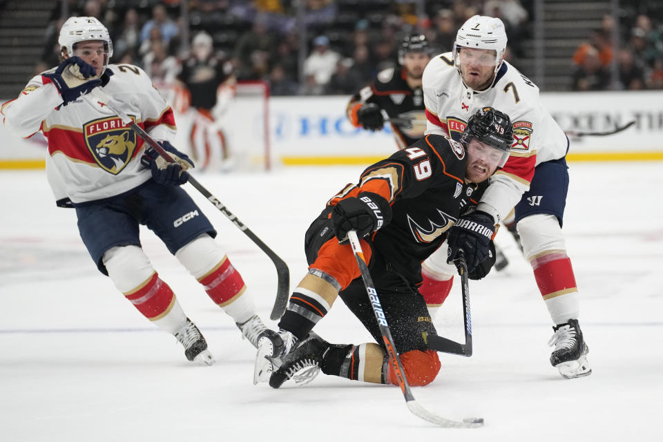 Anaheim Ducks left wing Max Jones (49) reaches for the puck against Florida Panthers defenseman Dmitry Kulikov (7) and center Nick Cousins (21) during the first period of an NHL hockey game in Anaheim, Calif., Friday, Nov. 17, 2023. (AP Photo/Ashley Landis)