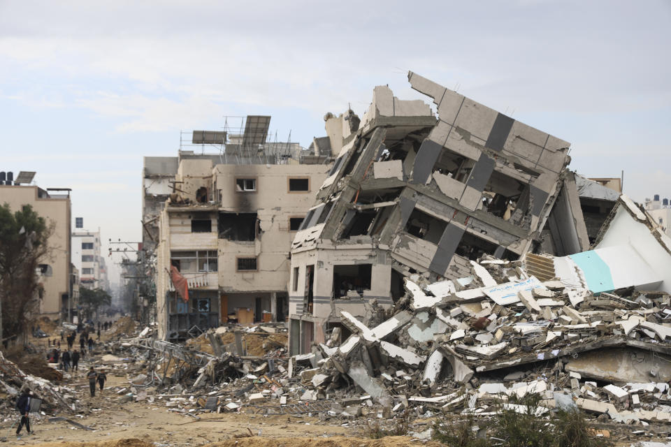 Palestinians walk past the building destroyed in the Israeli Bombardment of the Gaza Strip in Gaza City on Wednesday, Jan. 3, 2024. (AP Photo/Mohammed Hajjar)