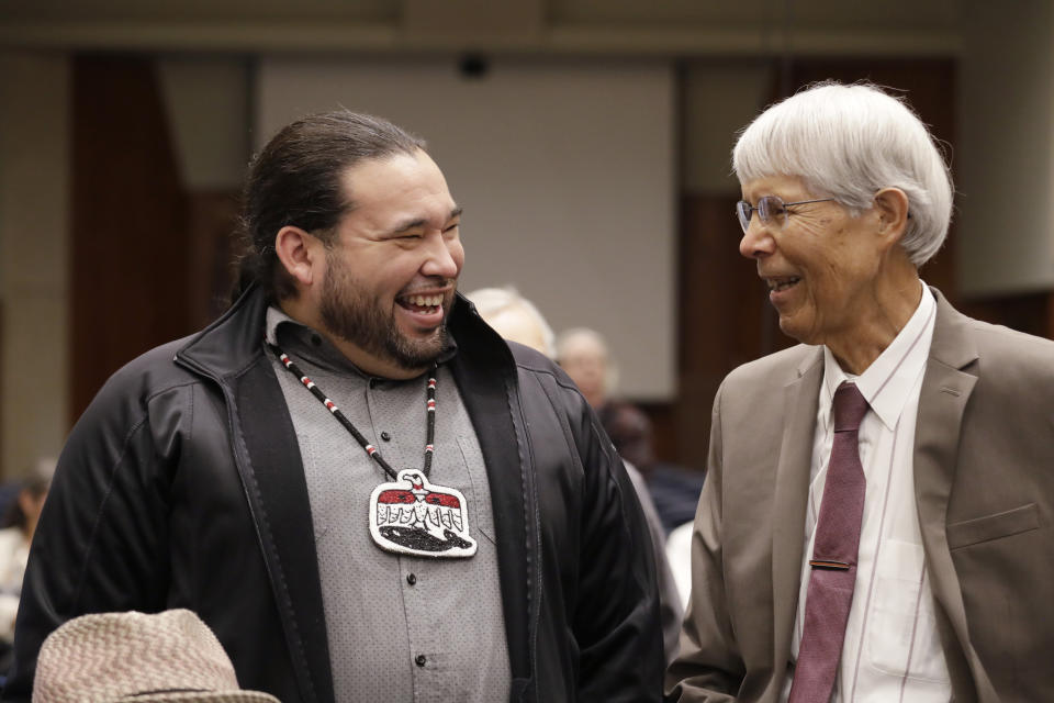 Makah Tribal Council Member Patrick DePoe, left, talks with Marine Mammal Commission Commissioner Michael F. Tillman before a federal court hearing to help determine whether DePoe's small American Indian tribe can once again hunt whales, Thursday, Nov. 14, 2019, in Seattle. The symbol DePoe wears is from the tribe's flag, and includes bird and whale symbols. The Makah Tribe, from the northwest corner of Washington state, conducted its last legal hunt in 1999, when its crew harpooned a gray whale from a cedar canoe. (AP Photo/Elaine Thompson)