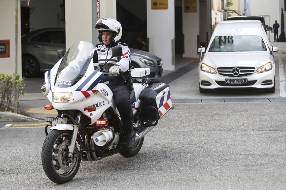 A police motorcycle escorts a hearse, right, carrying the body of former Zimbabwe President Robert Mugabe leaving the Singapore Casket Funeral Parlour for the airport in Singapore Wednesday, Sept. 11, 2019. Mugabe died Friday, Sept. 6 at a hospital in Singapore at age 95. (AP Photo/Danial Hakim)