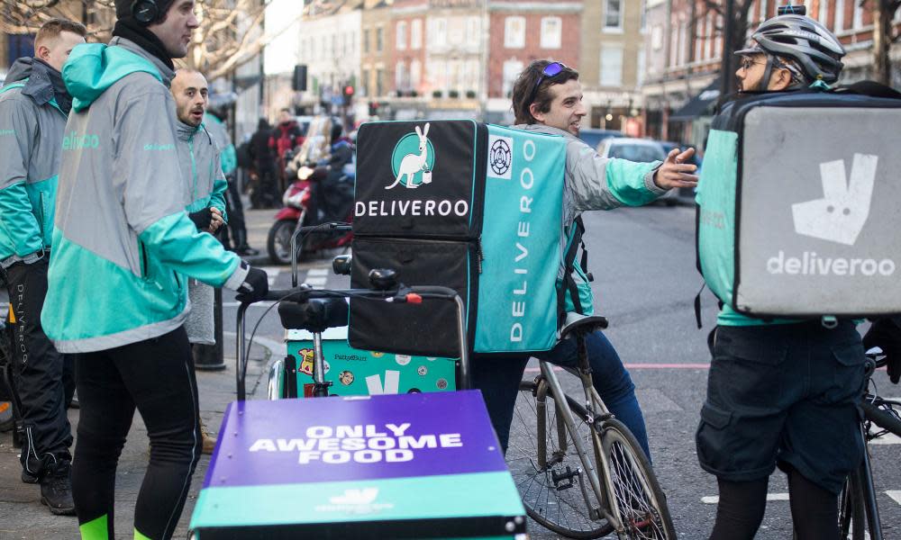 Food delivery cycle couriers chat as they wait for orders from Deliveroo.