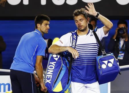 Novak Djokovic (L) of Serbia watches as Stan Wawrinka of Switzerland walks off the court after their men's singles semi-final match at the Australian Open 2015 tennis tournament in Melbourne January 30, 2015. REUTERS/Issei Kato