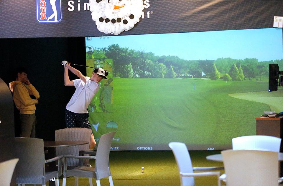 Kaden Dickerson tees off as Grady Cline watches while playing a round of golf on one of the simulators at Caddy Shack, 1640 Claremont Ave., Ashland.