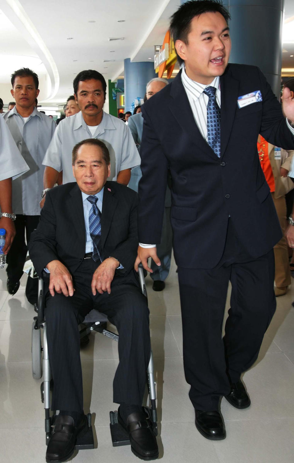 FILE – In this May 20, 2006 file photo, Henry Sy Sr., left, patriach of the Sy family and chairman of the SM Prime Holdings Inc. sits on the wheel chair as he is escorted by his grandson Hans Sy Jr. right, during the opening of the SM Mall of Asia in suburban Pasay City, south of Manila, Philippines. Macau gambling company Melco Crown Entertainment is teaming up with the Philippines’ richest man to develop a $1 billion Manila casino resort in a sign of the industry’s plans for rapid expansion in Asia. Melco said late Thursday, July 5, 2012 it will develop the project with three companies controlled by Philippine tycoon Henry Sy. Melco is jointly controlled by Lawrence Ho, who is the son of Macau casino king Stanley Ho, and by James Packer, the son of late Australian media magnate Kerry Packer. (AP Photo/Pat Roque, File)