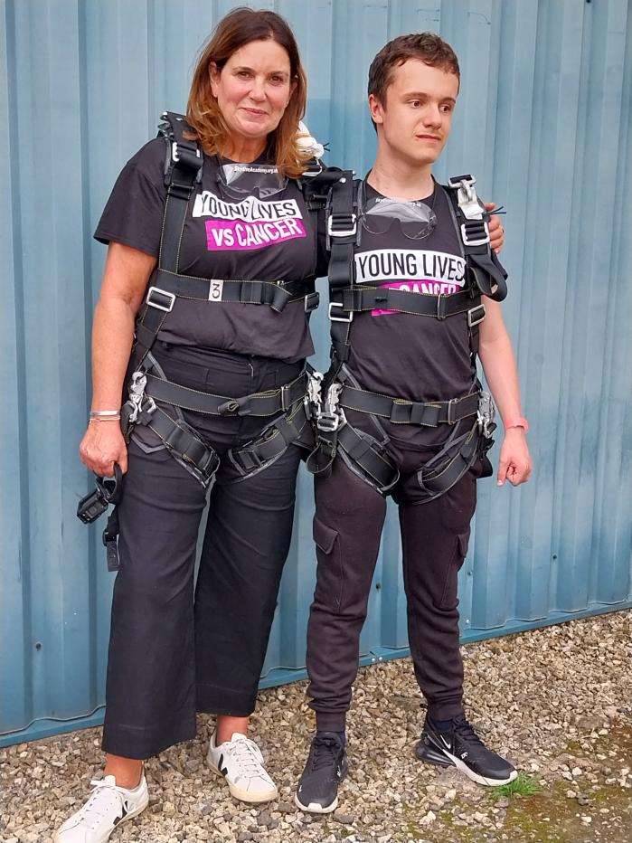 Two people standing together in skydiving equipment 