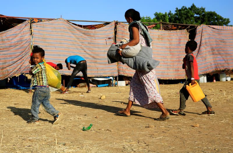 An Ethiopian woman and her children who fled war in Tigray region, carry their belongings as they arrive at the Um-Rakoba camp, on the Sudan-Ethiopia border in Al-Qadarif state