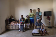 The family of Ali Kinno pose for a photograph from left to right, Fatmeh Kinno, 45, Mahmoud, 25, Hoda 11, Qoteiba 17, Mustafa, 28, Ali, 45, Ahmad, 6 during an interview at a temporary apartment in the coastal town of Jiyeh, south of Beirut, Lebanon, Tuesday, Sept. 15, 2020. The Kinno family from Syria's Aleppo region was devastated in the wake of the Aug. 4 explosion at the Beirut port, their tragic story reflects the particular pain of Syrian refugee families in Lebanon, which is now home to about a million Syrians. (AP Photo/Hassan Ammar)