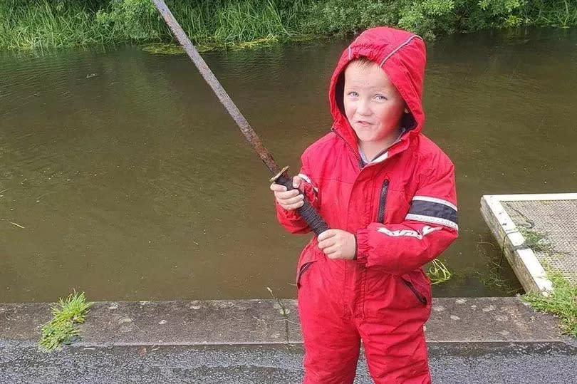 Mark's son James holding a samurai sword pulled from the water