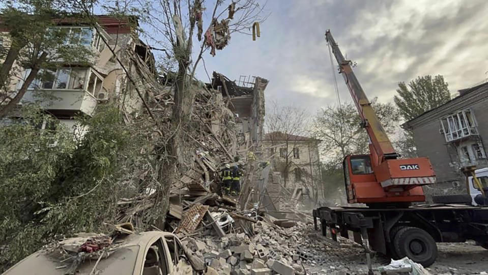 En esta fotografía proporcionada por el servicio de emergencias de Ucrania, rescatistas trabajan en el sitio en el que un edificio fue impactado por ataques, el jueves 6 de octubre de 2022, en Zaporiyia, Ucrania. (Servicio de Emergencias de Ucrania vía AP)