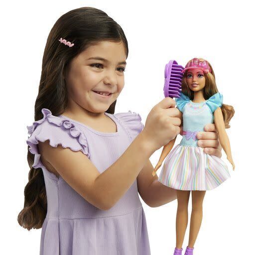 This image released by Mattel shows a child playing with Teresa, a My First Barbie, a new doll made specifically for children as young as 3. It is 13.5 inches tall, with a broader waste that de-emphasizes the bust line, with flesh-tone modesty undergarments permanently attached. (Mattel via AP)