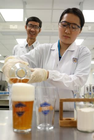 National University of Singapore (NUS) researchers Alcine Chan Mei Zhi (R) and Associate Professor Liu Shao Quan pour a pint of "gut-friendly" probiotic sour beer, which incorporates a probiotic strain that helps to neutralise toxins, at their Faculty of Science lab in Singapore July 14, 2017. REUTERS/Edgar Su