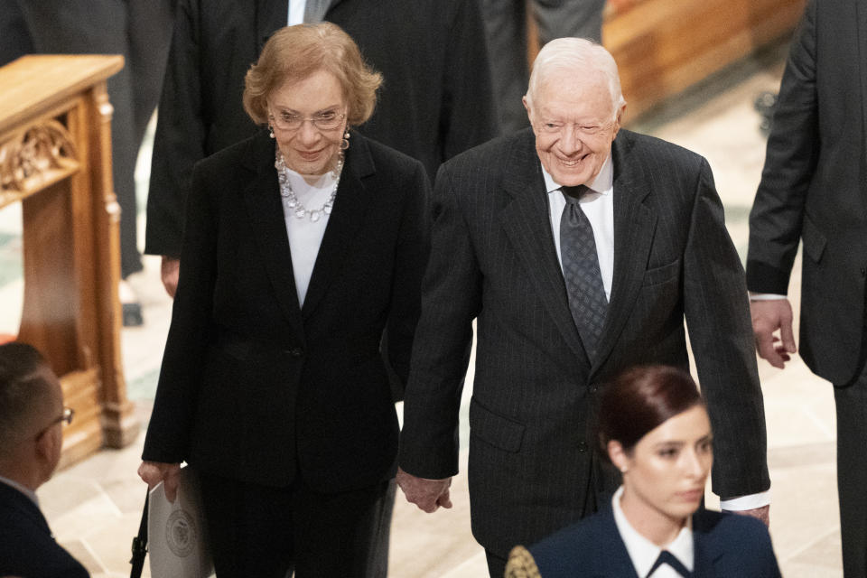 Former President Jimmy Carter, and Rosalynn Carter hold hands as they walk from a State Funeral for former President George H.W. Bush at the National Cathedral, Wednesday, Dec. 5, 2018, in Washington. (AP Photo/Carolyn Kaster)