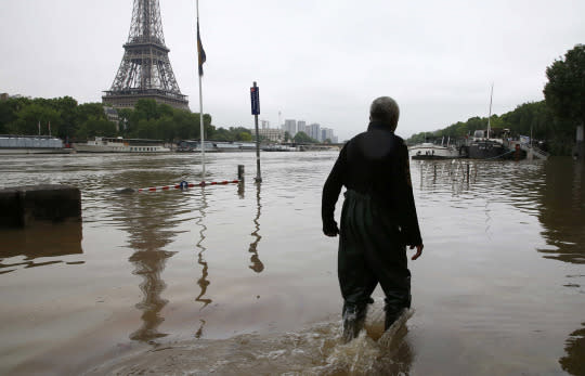 <p>A man trudges past the Eiffel Tower after days of almost nonstop rain, June 2, 2016. (Photo: Pascal Rossignol/Reuters) </p>
