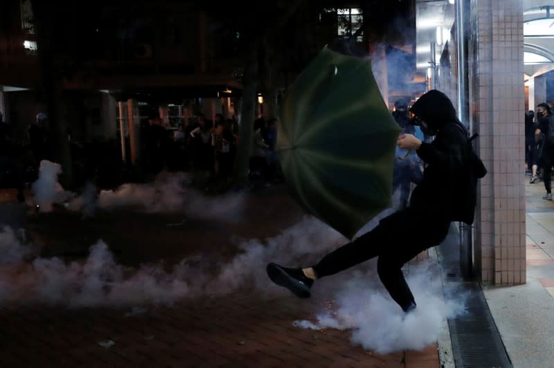 Anti-government protesters kicks a tear gas canister during a protest following 22 year-old University student's fall and who was critically injured last weekend, in Tseung Kwan O, Hong Kong