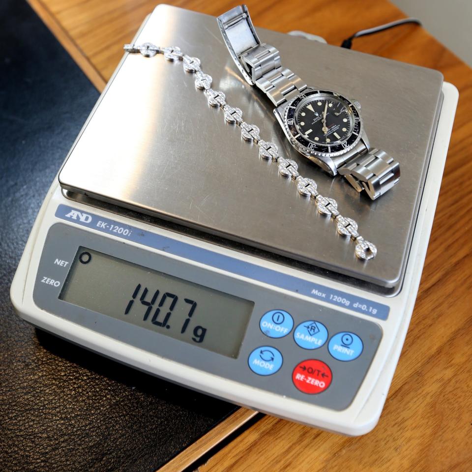 A Cartier bracelet and a Rolex wristwatch are weighed by Jim Tannahill as part of the authentification process