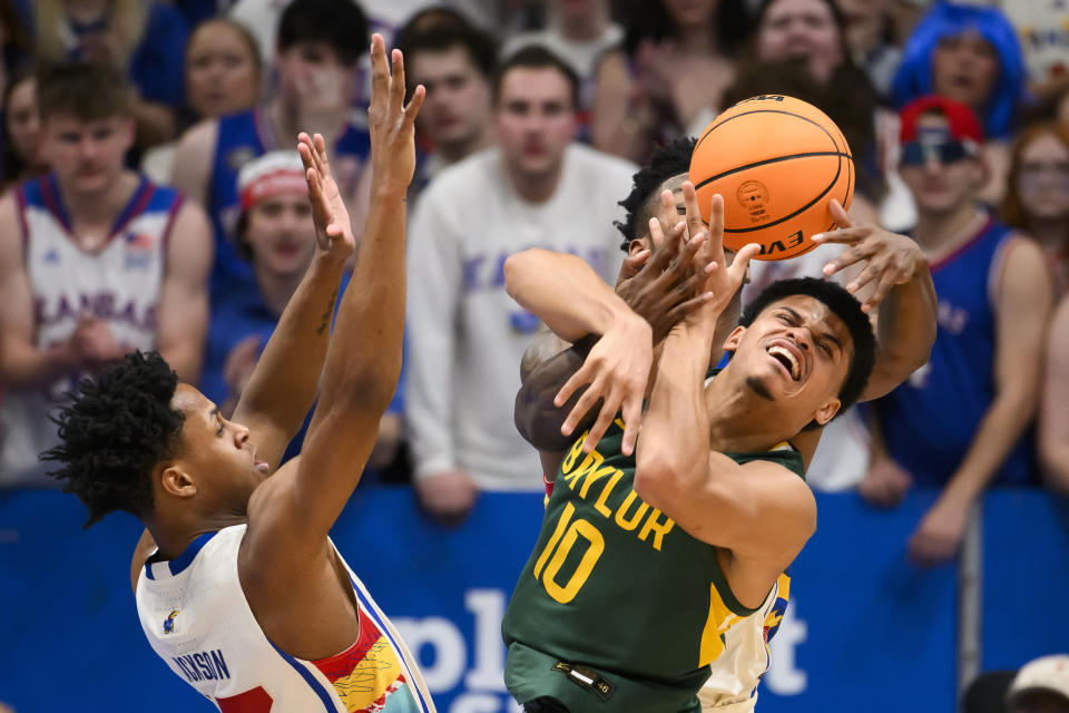 Baylor guard RayJ Dennis (10) tangles up with Kansas forward K.J. Adams Jr., in back, and Kansas guard Elmarko Jackson, left, during the first half of an NCAA college basketball game in Lawrence, Kan., Saturday, Feb. 10, 2024. (AP Photo/Reed Hoffmann)