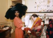 <p>French fashion designer Christian Lacroix works on his 1987 spring-summer haute couture line for Patou. Fashion model Kadija is wearing a large black hat with a rose-colored dress.</p>