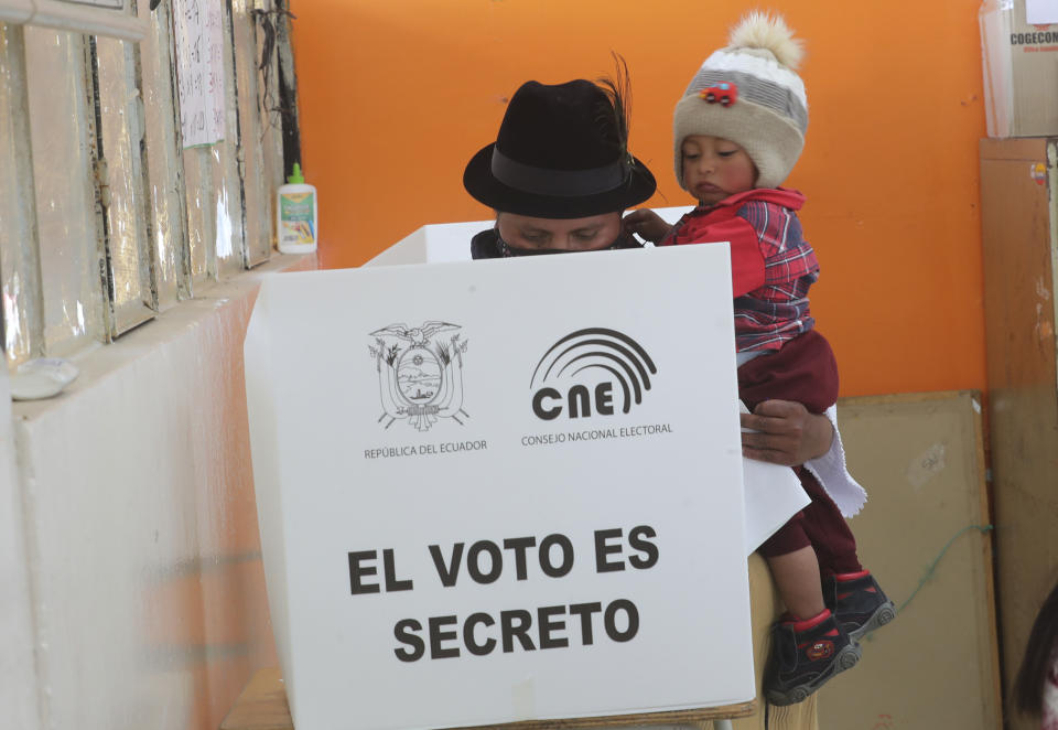 A woman carries her son as she casts her ballot in a general election, in Cangahua, Ecuador, Sunday, Feb. 7, 2021. Amidst the new coronavirus pandemic, Ecuadoreans went to the polls in a first-round presidential and legislative election. (AP Photo/Dolores Ochoa)