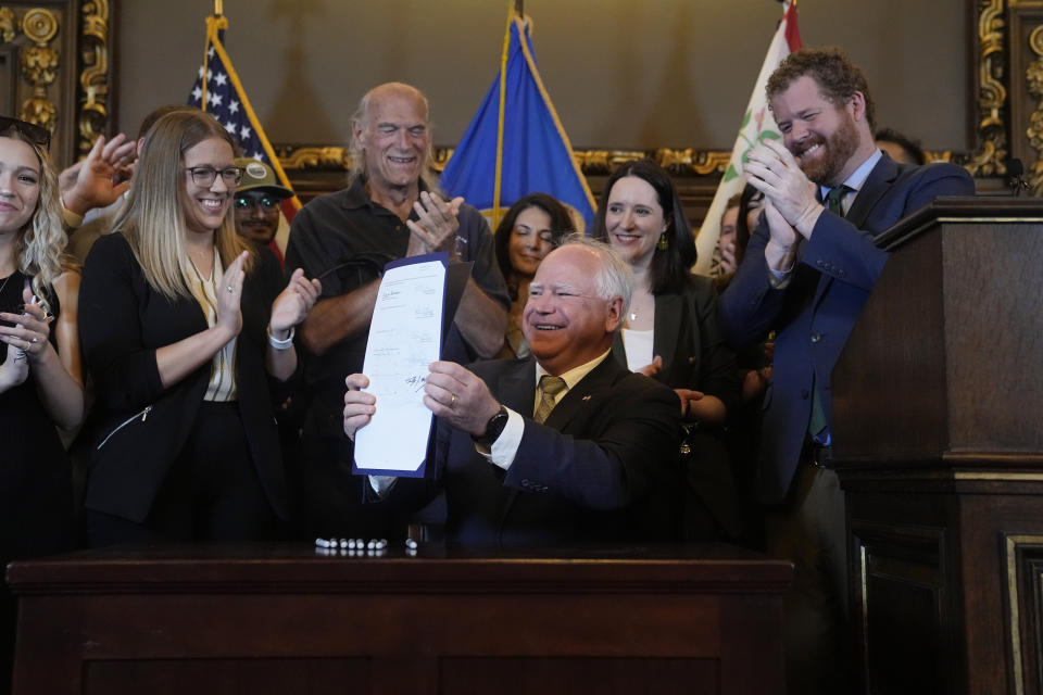 Minnesota Gov. Tim Walz, middle, holds the bill signed to legalize recreational marijuana for people over the age of 21, making Minnesota the 23rd state to do so, Tuesday, May 30, 2023, in St. Paul, Minn. Former Gov. Jesse Ventura stands at center. (AP Photo/Abbie Parr)