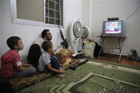 A Free Syrian Army fighter watches U.S. President Barack Obama's speech with his family in Ghouta, Damascus August 31, 2013. REUTERS/ Mohamed Abdullah