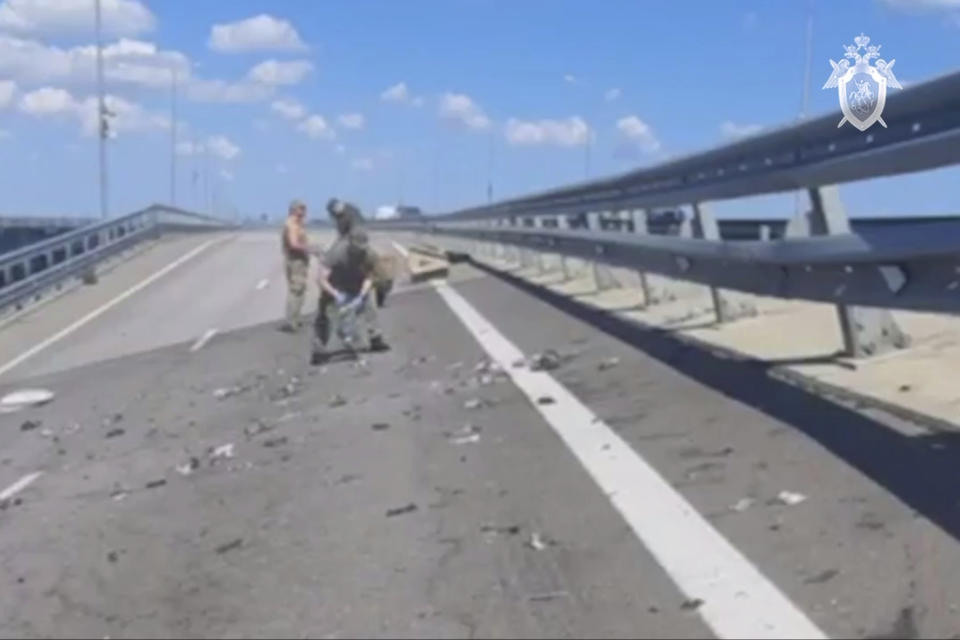 In this handout photo taken from video released by Investigative Committee of Russia on Monday, July 17, 2023, investigators work at an automobile link of the Crimean Bridge connecting Russian mainland and Crimean peninsula over the Kerch Strait not far from Kerch, Crimea. Traffic on the key bridge connecting Crimea to Russia's mainland was halted on Monday, July 17, after reports of explosions that Crimean officials said were from a Ukrainian attack. (Investigative Committee of Russia via AP)