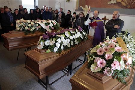 A priest blesses three coffins during a funeral service for some victims of an extreme rainfall at Tempio Pausania on Sardinia island November 20, 2013. REUTERS/Tony Gentile